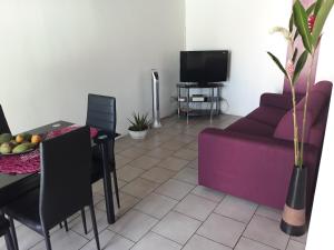 uma sala de estar com um sofá roxo e uma mesa em villa do brazil em Ducos