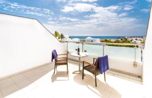 a balcony with a table and chairs and the ocean at Hotel Lanzarote Village in Puerto del Carmen