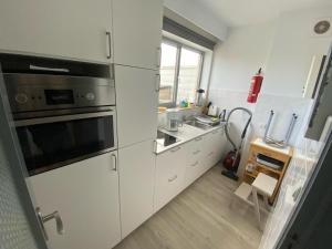 uma cozinha com armários brancos e um forno com placa de fogão em Roof Studio with Large Sun Terrace in Middelkerke em Middelkerke