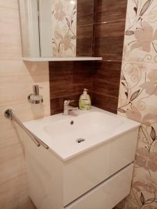 een badkamer met een witte wastafel en een spiegel bij Éva Vendégház in Tata