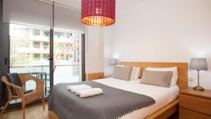 a bedroom with a bed with a chair and a window at RAMBLA BEACH Barcelonastuff Apartments in Barcelona