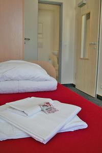 a pair of white towels sitting on a red bed at CVJM Jugendgästehaus Berlin in Berlin