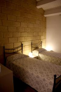 two beds in a room with a brick wall at Casa vacanze Vendicari in Reitani