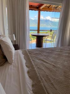 a bedroom with a bed with a view of the ocean at Hotel Vista Bella in Ilhabela