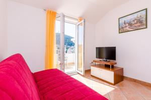 a living room with a red couch and a large window at Apartments Villa Perla in Dubrovnik