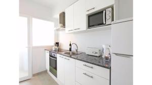 een witte keuken met een wastafel en een magnetron bij Apartamentos Sema in Son Servera