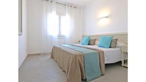 een slaapkamer met een bed met blauwe kussens bij Apartamentos Sema in Son Servera
