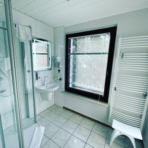 a white bathroom with a sink and a window at Appartement Seebadallee mit Wallbox für e-Autos in Rangsdorf