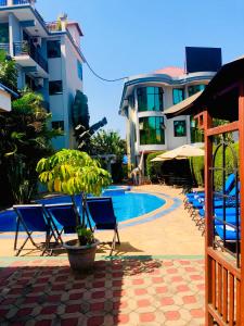 a pool with chairs and a tree next to a building at Green Mountain Hotel in Arusha