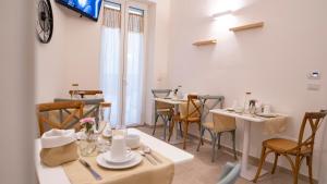 ein Esszimmer mit Tischen und Stühlen und einer Uhr an der Wand in der Unterkunft Dimora Fantasia Charme B&B in Bari