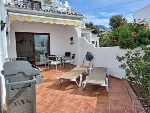 patio ze sprzętem do grillowania, stołem i krzesłami w obiekcie CAPISTRANO PUEBLO 106A Menyber w mieście Nerja