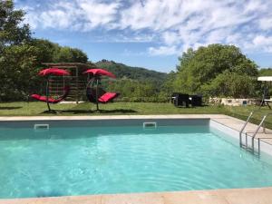 a pool with two red umbrellas and a playground at La Tenuta - Resort Agricolo in Casaprota