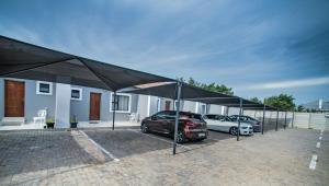 a parking lot with two cars parked under a canopy at Khayalami Hotel - Standerton in Standerton