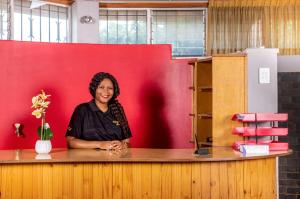 a woman sitting at a counter in front of a red wall at Khayalami Hotel - Standerton in Standerton