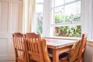 mesa de comedor con 3 sillas y ventana en Lovely Sunny 2 Bed Home Edinburgh Coast, en Edimburgo
