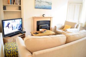 a living room with a couch and a television at Lovely Sunny 2 Bed Home Edinburgh Coast in Edinburgh