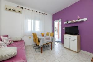 un soggiorno con tavolo e parete viola di Apartman Pandula a Tkon (Tuconio)