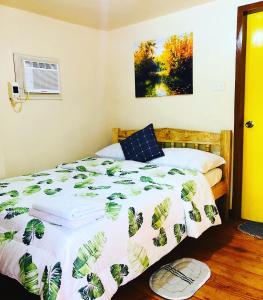 Schlafzimmer mit einem Bett mit einer grünen und weißen Bettdecke in der Unterkunft Domos Native Guest House in Panglao