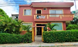 una casa rosa con balcón frente a ella en Hostal Terito, en Puerto Baquerizo Moreno