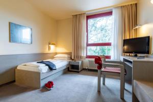 een slaapkamer met een bed, een bureau en een televisie bij Hotel Baden-Baden in Baden-Baden