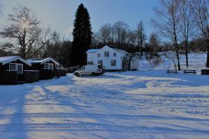 einen schneebedeckten Hof mit einem Haus und einem Auto in der Unterkunft Björsjöås Vildmark - Small camping cabin close to nature in Olofstorp