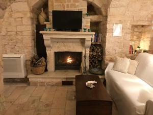 sala de estar con chimenea de piedra y TV en Trulli Aria di Casa, en Alberobello