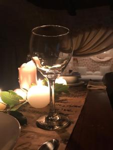 a wine glass sitting on a table with candles at Trulli Aria di Casa in Alberobello