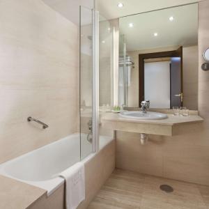 y baño con bañera, lavamanos y ducha. en NH Imperial Playa, en Las Palmas de Gran Canaria
