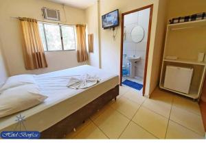 a bedroom with a bed and a bathroom with a television at Hotel Benfica in Aparecida