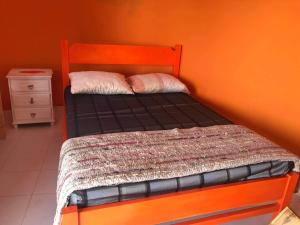 Cama pequeña en habitación con pared de color naranja en Casa helena, en Portela