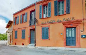 un edificio naranja con persianas azules en una calle en Maison de Save, en LʼIsle-Jourdain
