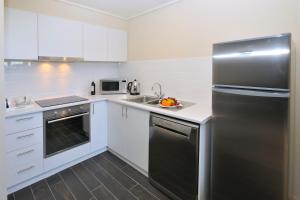 a kitchen with stainless steel appliances and white cabinets at Grand Hotel Melbourne in Melbourne