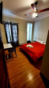 een slaapkamer met een rood bed en een plafondventilator bij Hotel Positano in Mar del Plata
