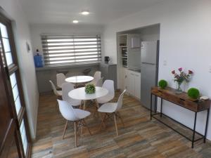 uma cozinha e sala de jantar com duas mesas e cadeiras brancas em Carolina Hostal em Viña del Mar