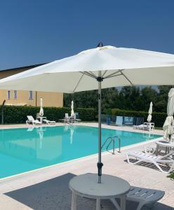 - un parasol blanc à côté de la piscine dans l'établissement Villa Zanina Sonia Apartment, à Peschiera del Garda