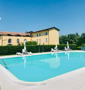 a large swimming pool with chairs and a building in the background at Villa Zanina Sonia Apartment in Peschiera del Garda