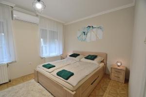 ハイドゥソボスローにあるHuba Apartman 2.のベッドルーム1室(大型ベッド1台、緑の枕付)