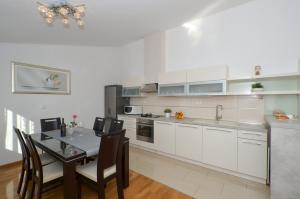 uma cozinha com armários brancos e uma mesa com cadeiras em Apartmani Adela em Solin