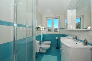 baño azul y blanco con 2 aseos y lavamanos en Apartmani Adela en Solin