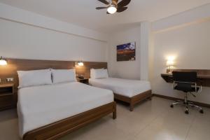 a hotel room with two beds and a desk at Hotel Alexander in Trujillo