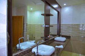 a bathroom with two sinks and a large mirror at Hotel SAHARATEL in Laayoune