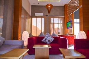 a living room with a red couch and tables at Hotel SAHARATEL in Laayoune