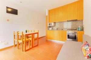 una cocina con armarios de madera y una mesa con sillas. en Aparthotel Gerês, en Gerês