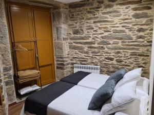 a bedroom with a bed and a stone wall at Casa da Marquesa Sarria in Sarria
