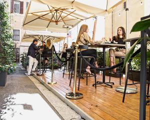 un groupe de personnes assises à des tables sur un patio dans l'établissement Roma Luxus Hotel, à Rome