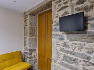 sala de estar con TV en una pared de piedra en Casa da Marquesa Sarria en Sarria