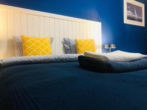 a bedroom with a bed with blue walls and yellow pillows at Villa La Via *** in Dunajská Streda