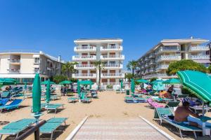 una spiaggia con sedie e ombrelloni e alcuni hotel di Residence Nautilus a Lido di Jesolo