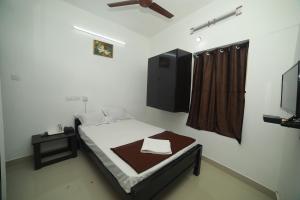 a small bedroom with a bed and a tv at MEGHNA RESIDENCY in Trivandrum