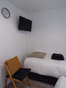 1 dormitorio con 1 cama, 1 silla y 1 reloj en City Beach AirBnB Southend on Sea,, en Southend-on-Sea